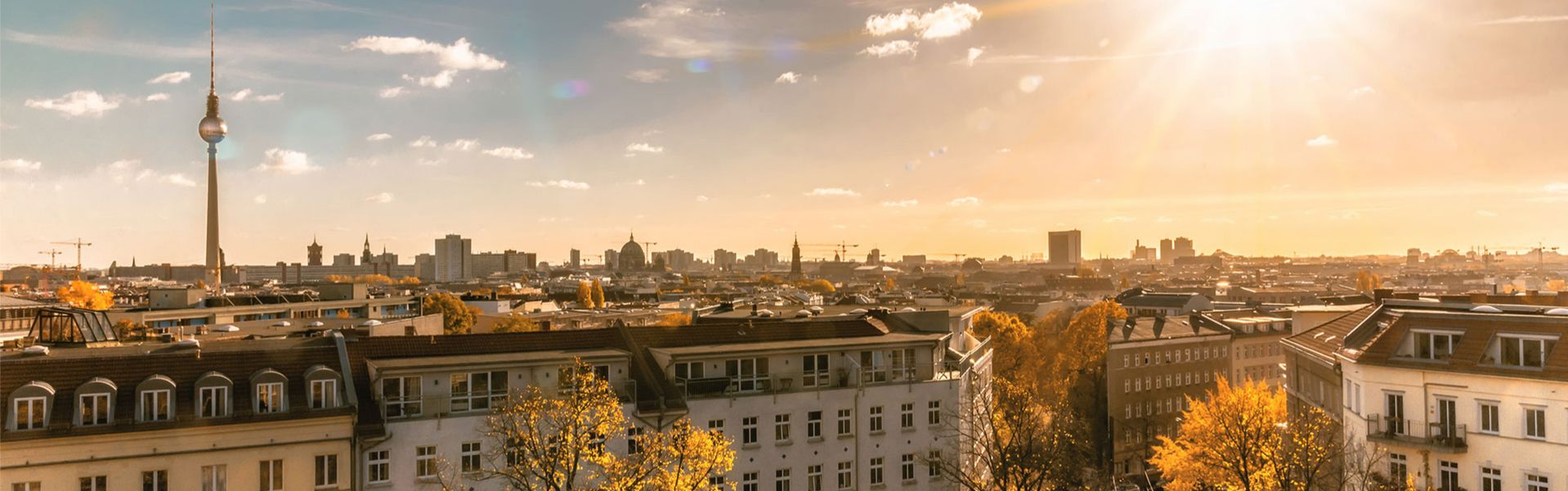 Stadtpanorama mit Fernsehturm und mehrstöckigen Wohngebäuden bei Sonnenuntergang
